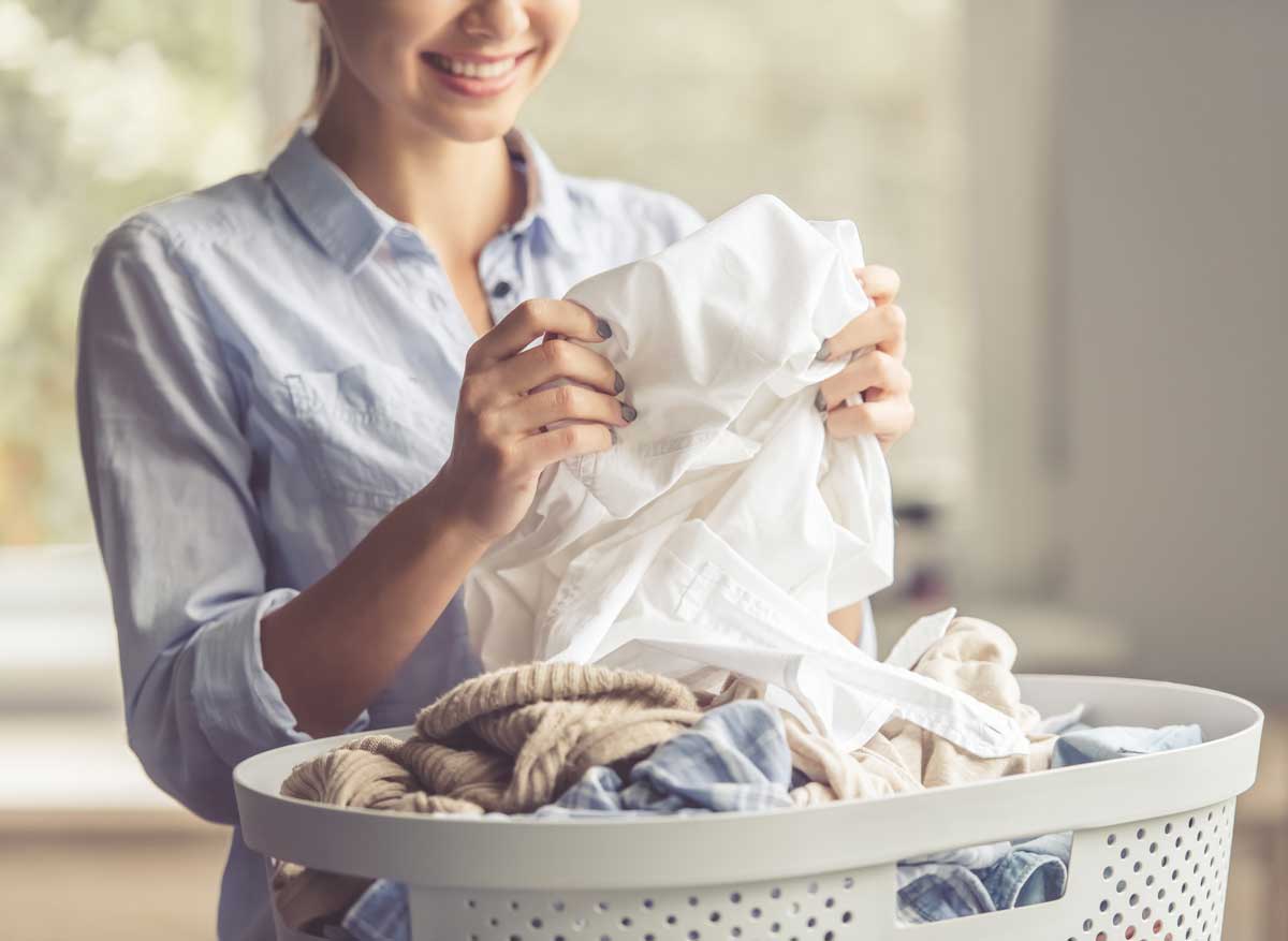 Cropped image of beautiful young woman is smiling while doing laundry at home